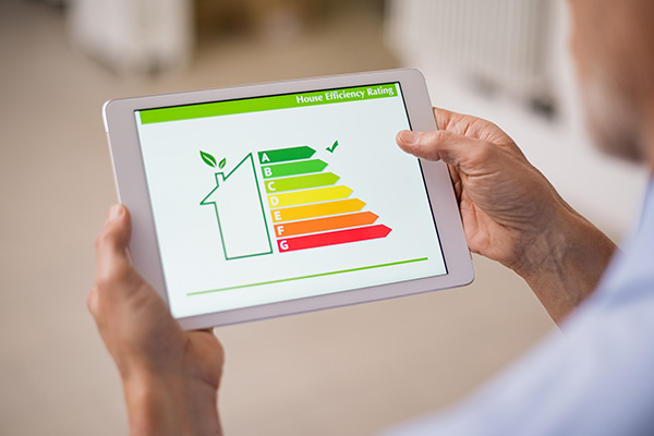 Hand holding digital tablet and looking at house efficiency rating.