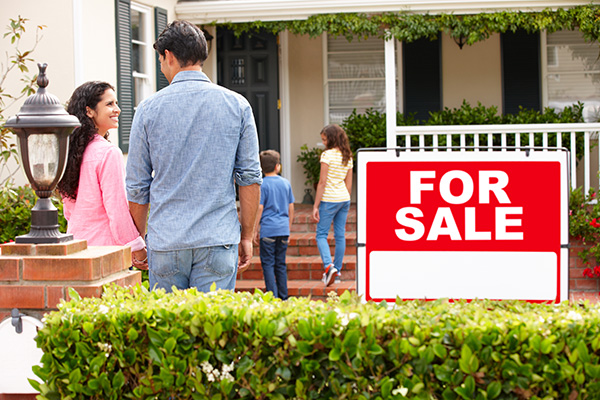 family outside home with for sale sign